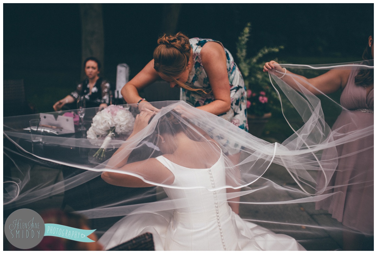 The bride gets some help with her veil.