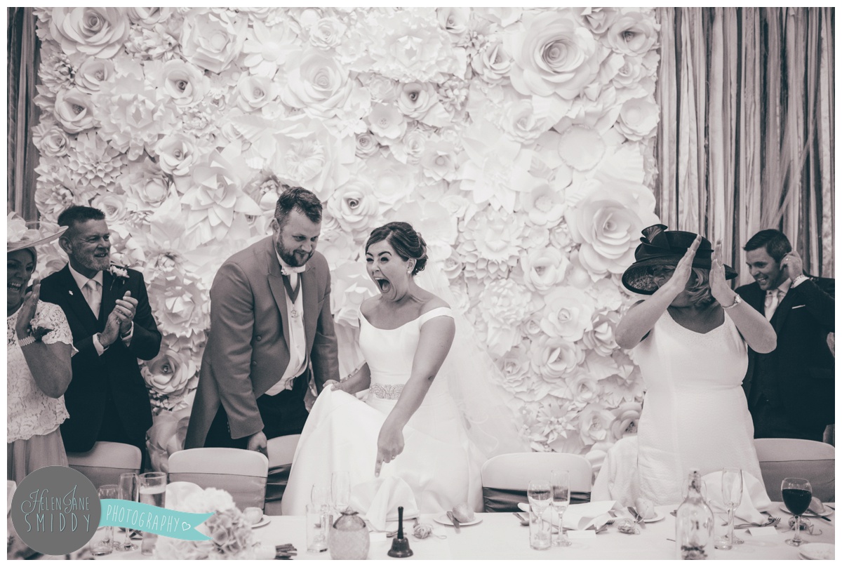 The bride sees her place setting and laughs at the decorations.
