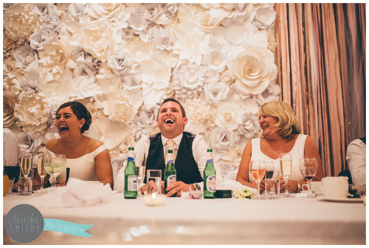 Groom laughs as his best man makes jokes during his speeches.