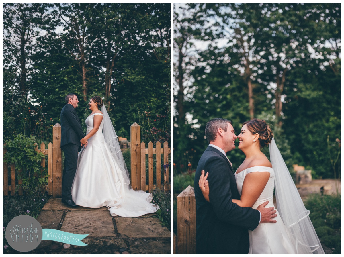 The bride and groom stand close together, chatting about their big day.