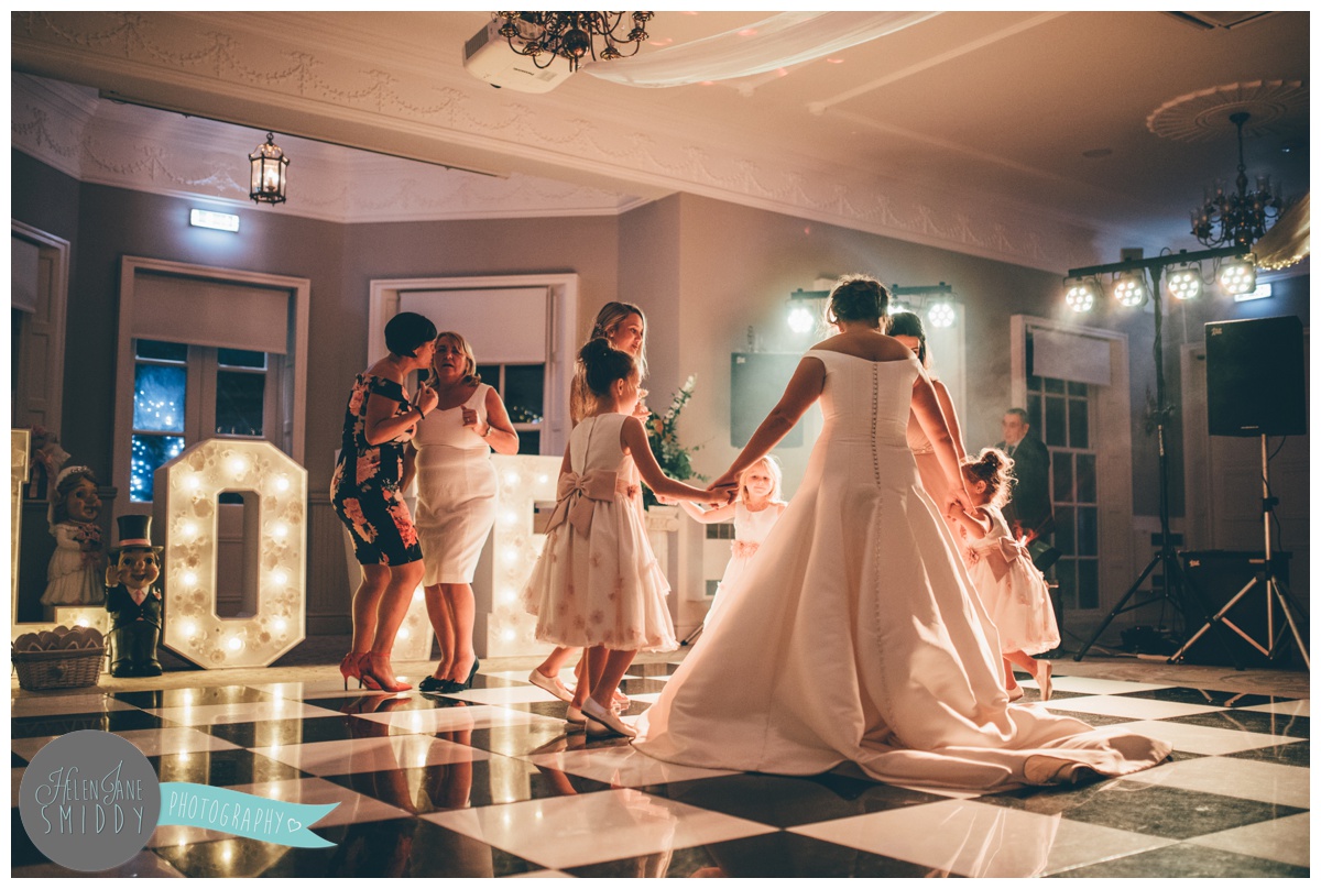 The bride dances on the beautifully lit dancefloor with her bridesmaids at Statham Lodge in Cheshire