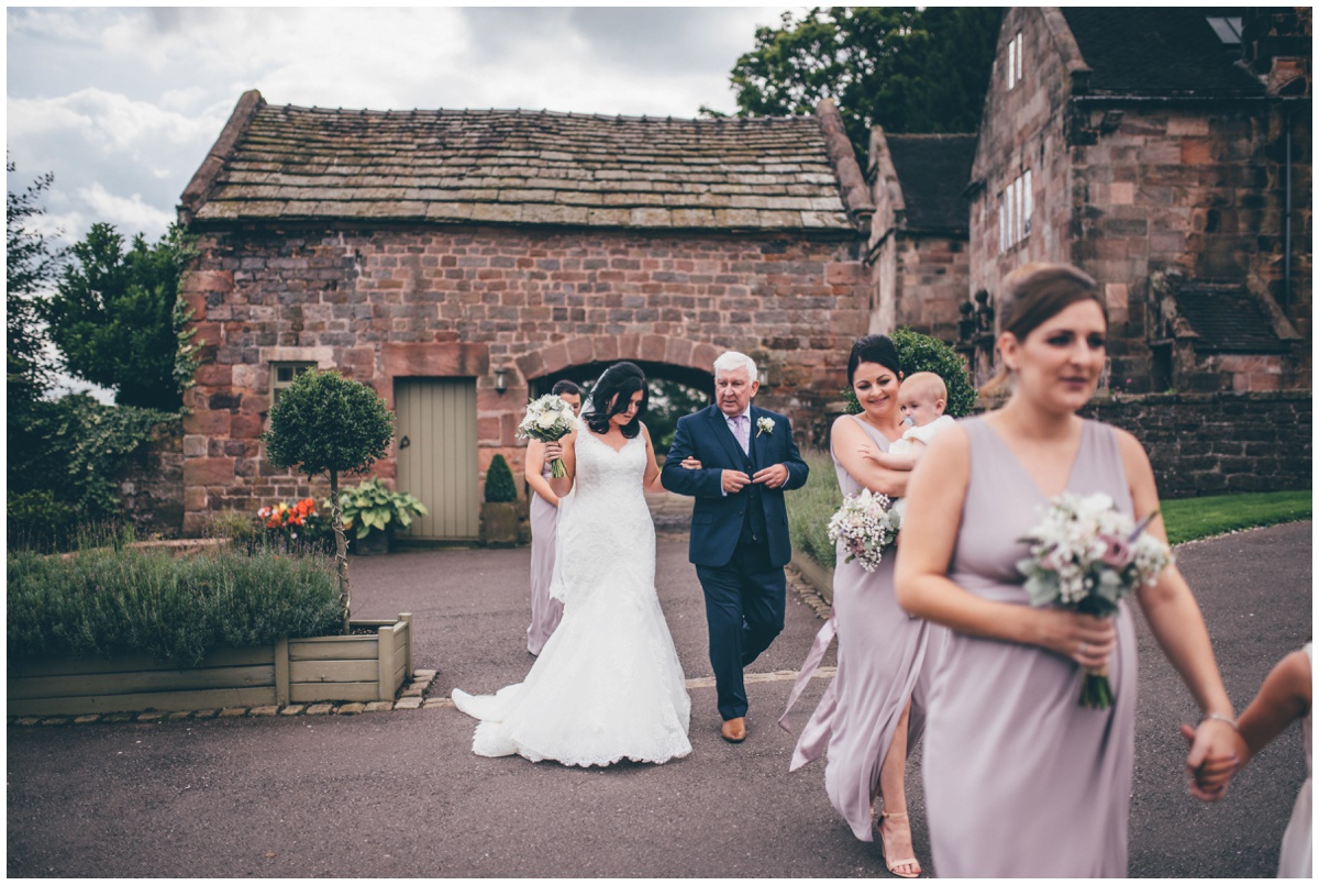 The bridesmaids lead the bride and her father into the ceremony room at The Ashes wedding barn in Staffordshire.