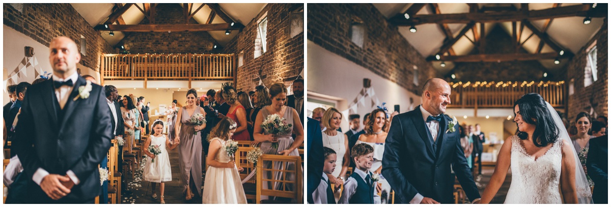 The bridesmaids lead the bride and her father into the ceremony room at The Ashes wedding barn in Staffordshire.