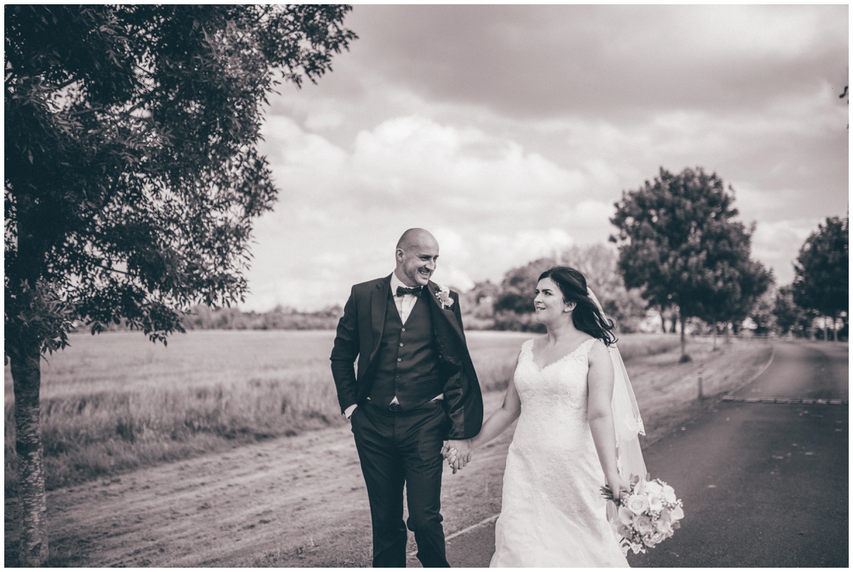 The bride and groom stroll, hand-in-hand towards their wedding venue, The Ashes wedding barn in Staffordshire.