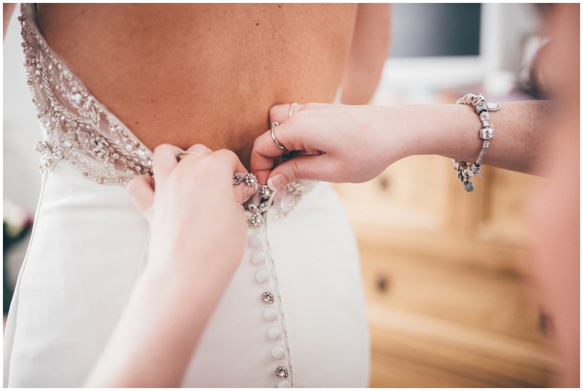 The bride's best friend fasten up her wedding dress.