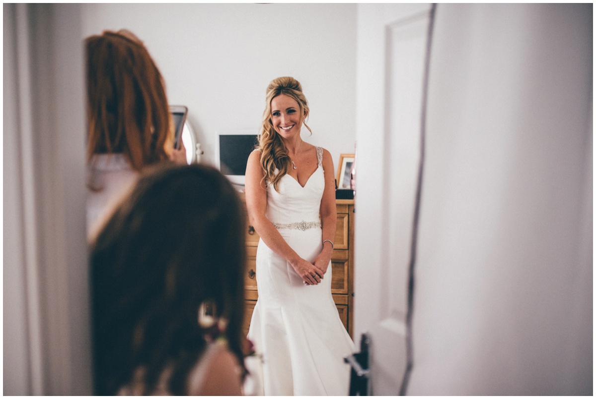 Bridesmaids look on as the beaming bride continues getting ready.