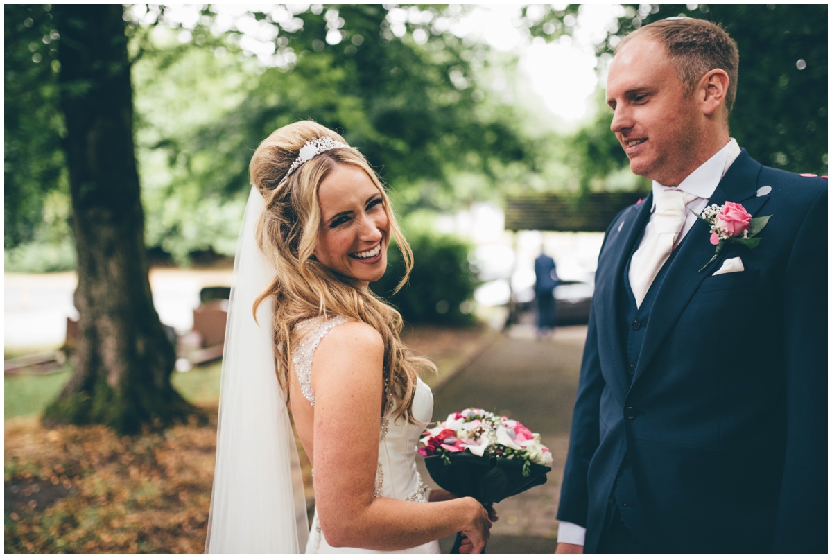 The beautiful bride beams at her Cheshire wedding photographer outsider her Worsley church.