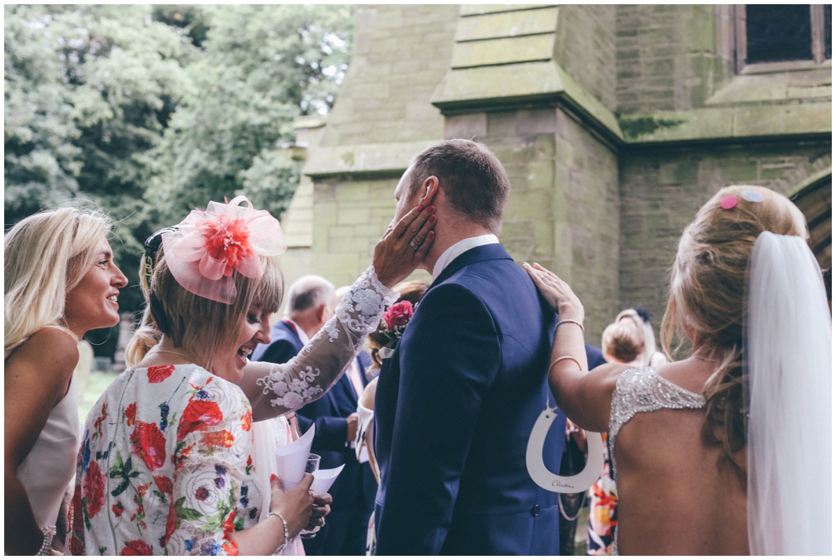 Both the bride and mother of the groom try to get the groom's attention outside St Mark's church in Worsley.