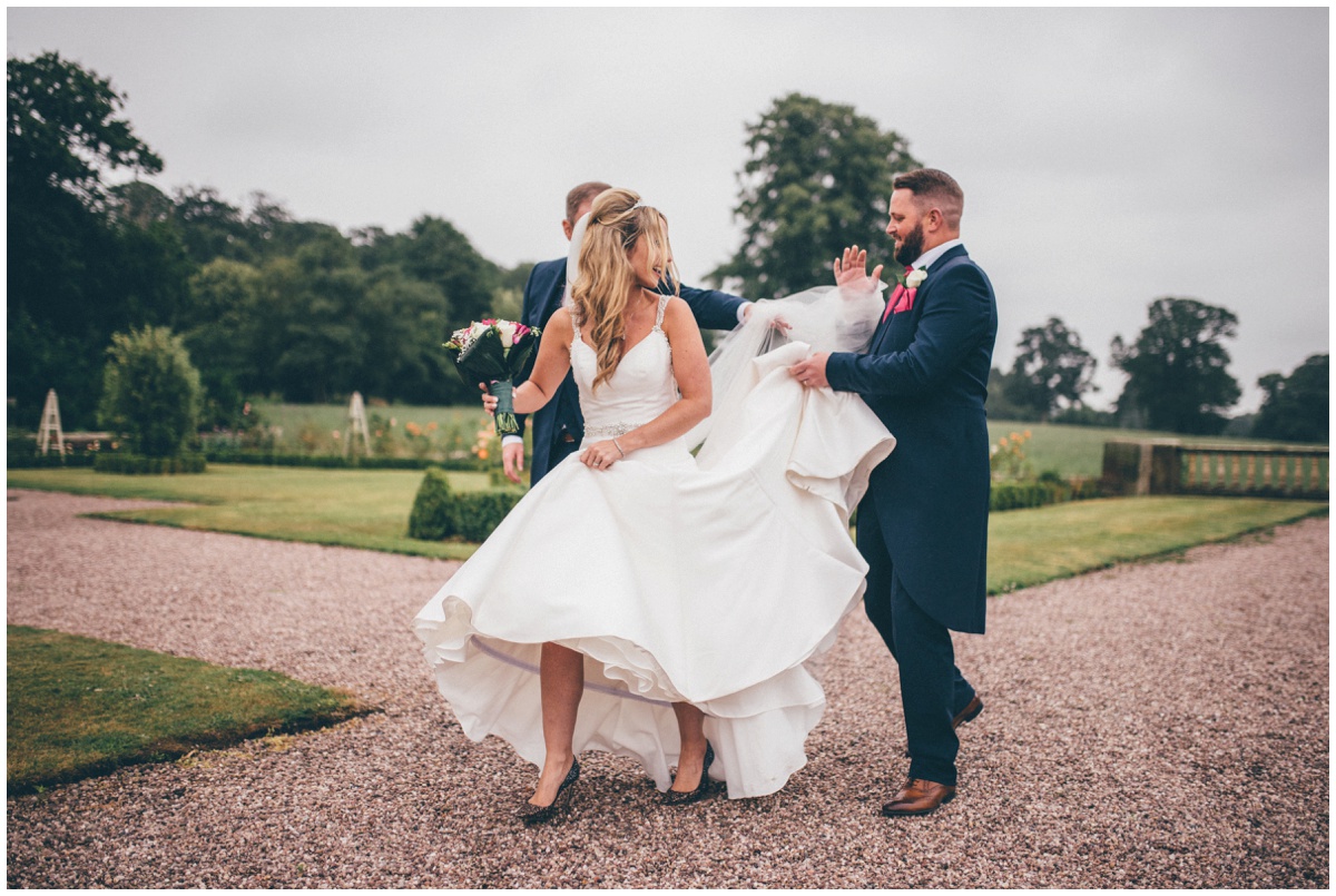 The groom and his Best Man help the bride, Deb, with her dress on the grounds of Willington Hall.