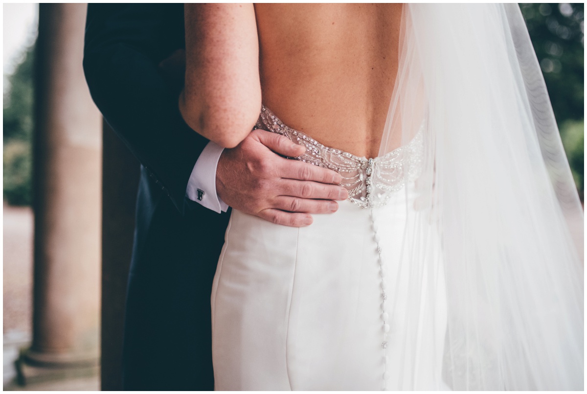 Close-up detail of the groom holding his new wife's waist in an embrace.