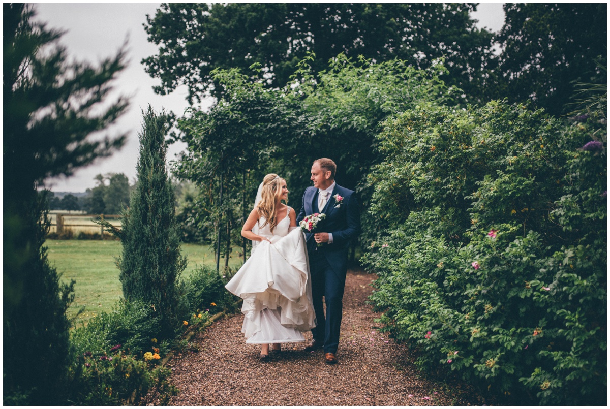 Happy groom helps his new wife walks through the pretty gardens.