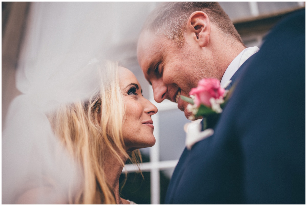 Cute newlyweds share a close moment under the bride's veil.
