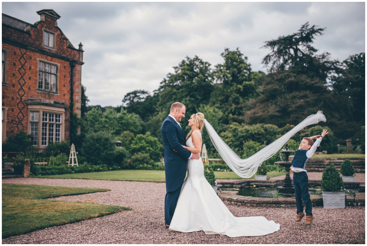 The adorable little pageboy helps the Cheshire wedding photographer by throwing the veil up in the wind.