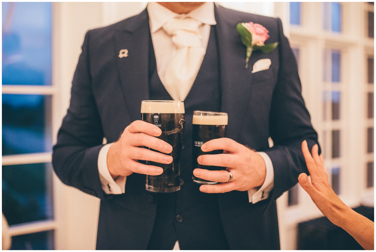 The groom holds his own pint of Guinness and his wife's half pint of Guinness at their wedding reception.