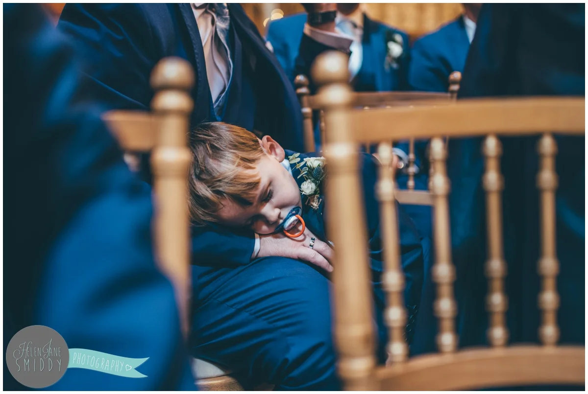 Cute little pageboy falls asleep during the wedding ceremony.