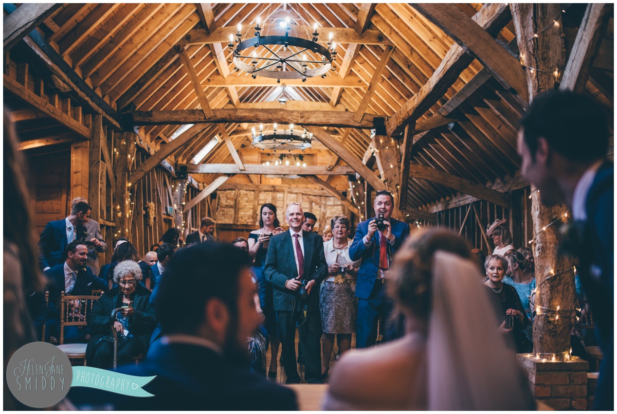 The wedding guests take photographs of the newlyweds signing their register.