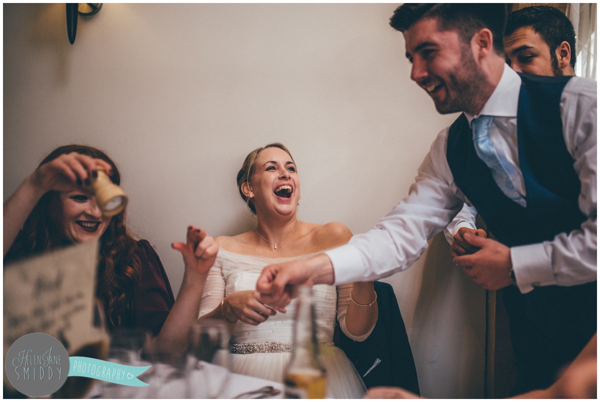 The bride laughs with her wedding guests over some shots of tequila.