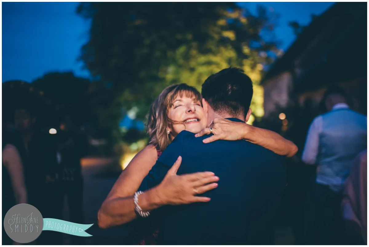The mother of the bride hugs a guest happily at the evening celebrations.