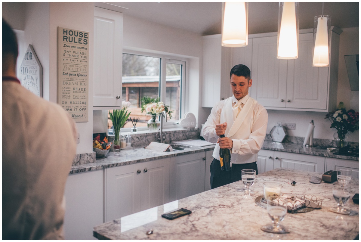 The groom opens a bottle of champagne for himself and his groomsmen.