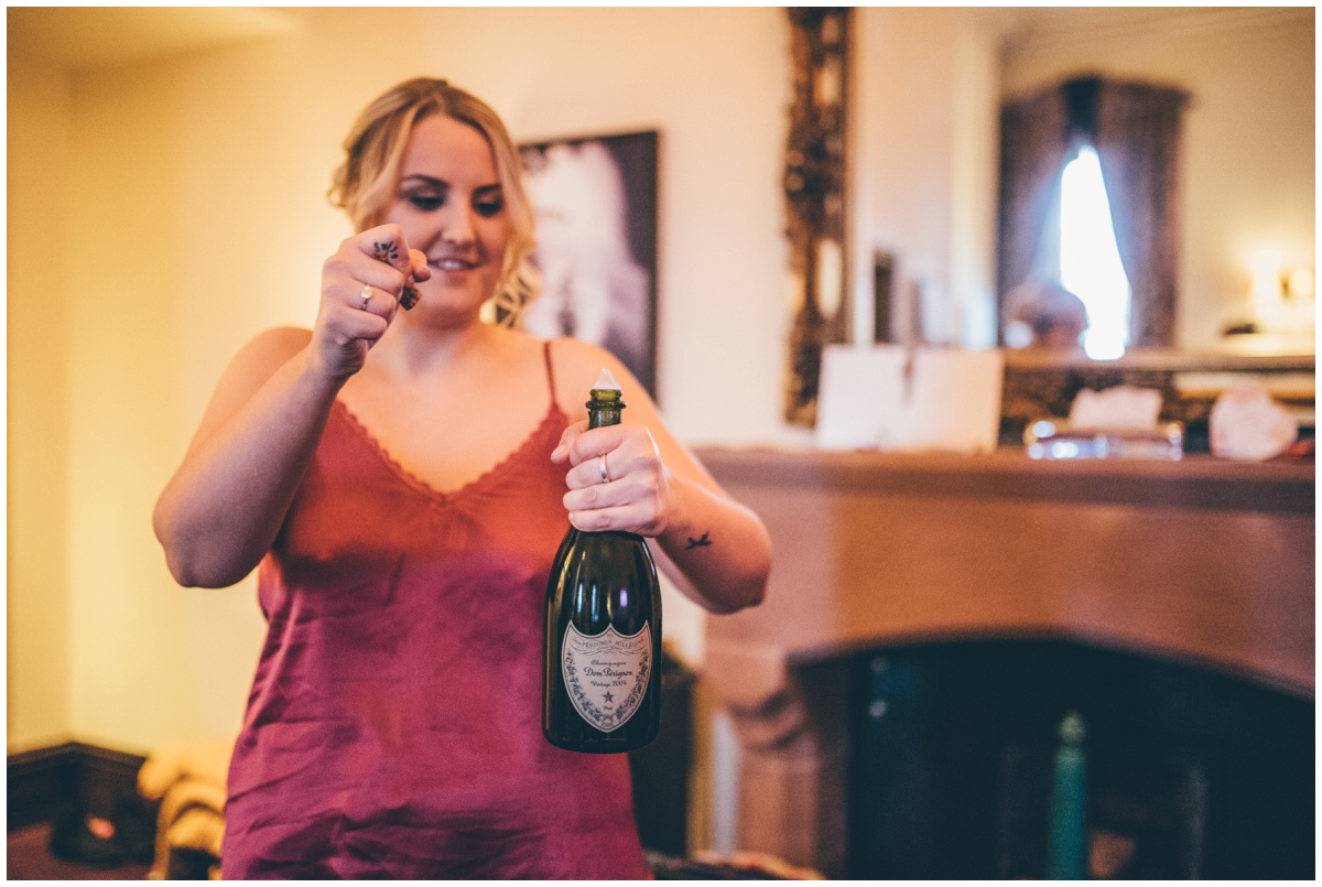 Bridesmaid opens a bottle of champagne on the wedding morning.