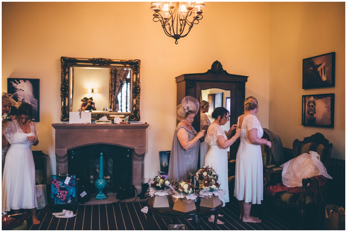 Bridesmaids all help each other dress before the wedding ceremony.