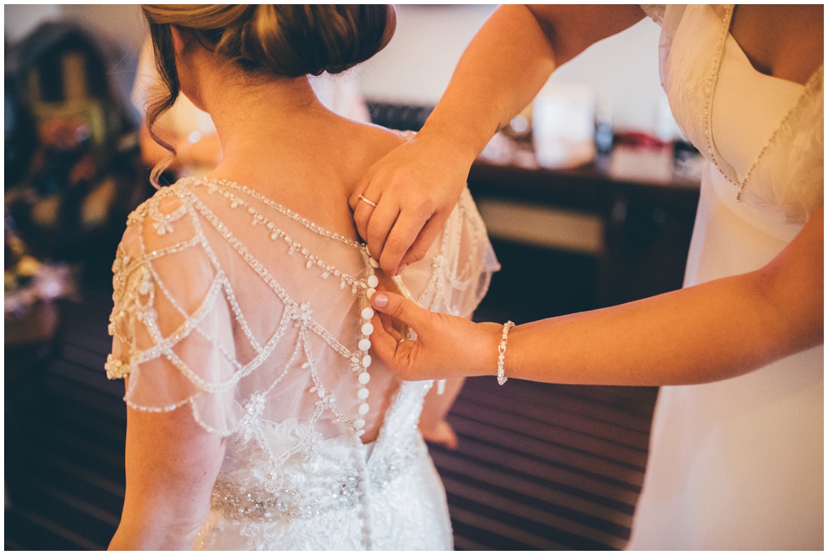 Sarah gets fastened into her wedding gown at Peckforton Castle.