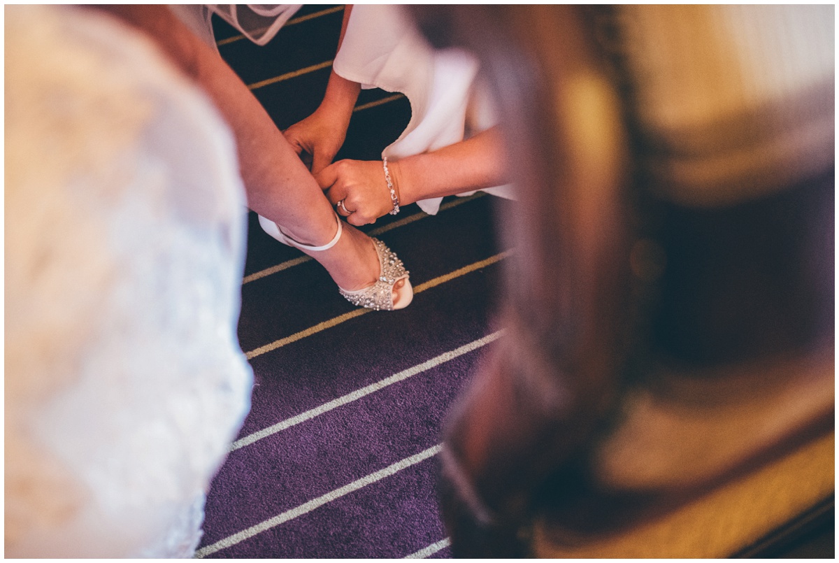 Maid of honour fastens the bride into her Jenny Packham wedding shoes.