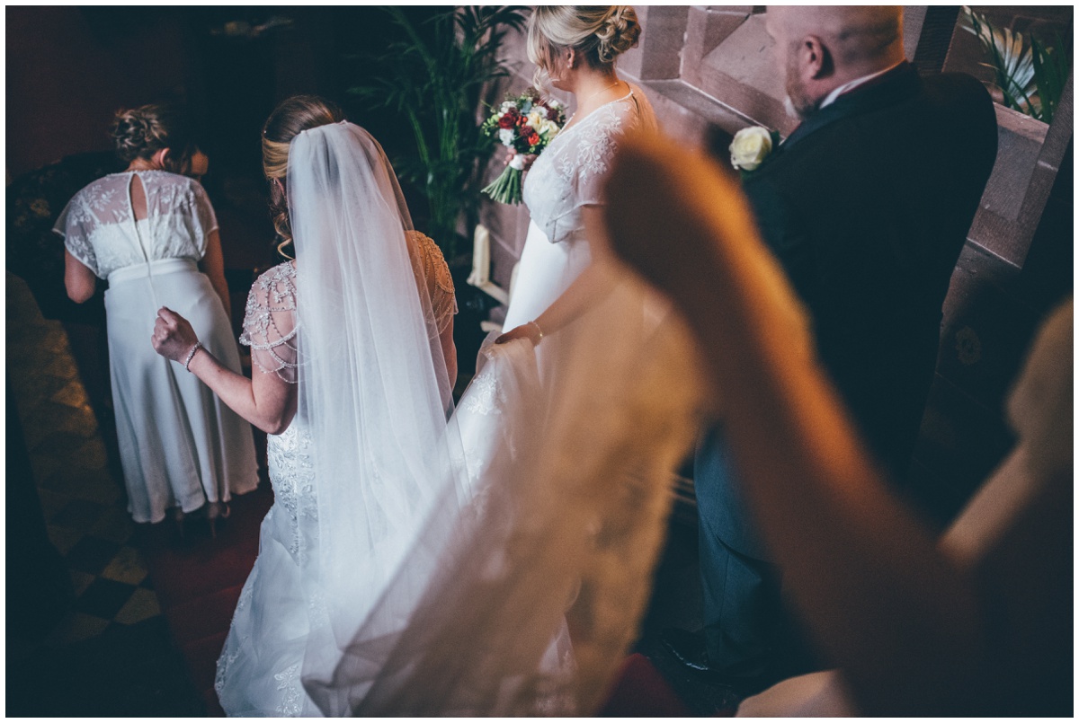Bridesmaids help the bride through Peckforton Castle.