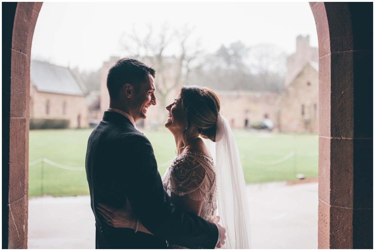 The new husband and wife have their wedding portraits taken in the doorway at Peckforton Castle.