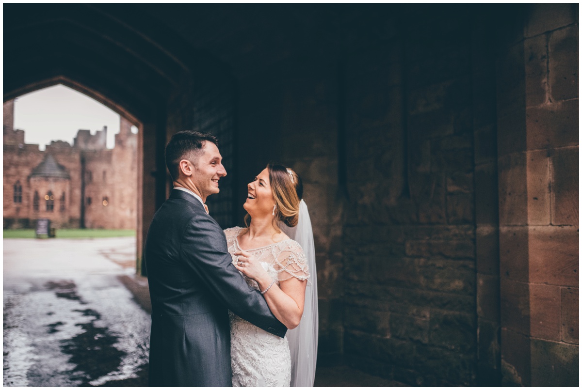 The bride and groom have their wedding photographs taken at the entrance of Peckforton Castle.