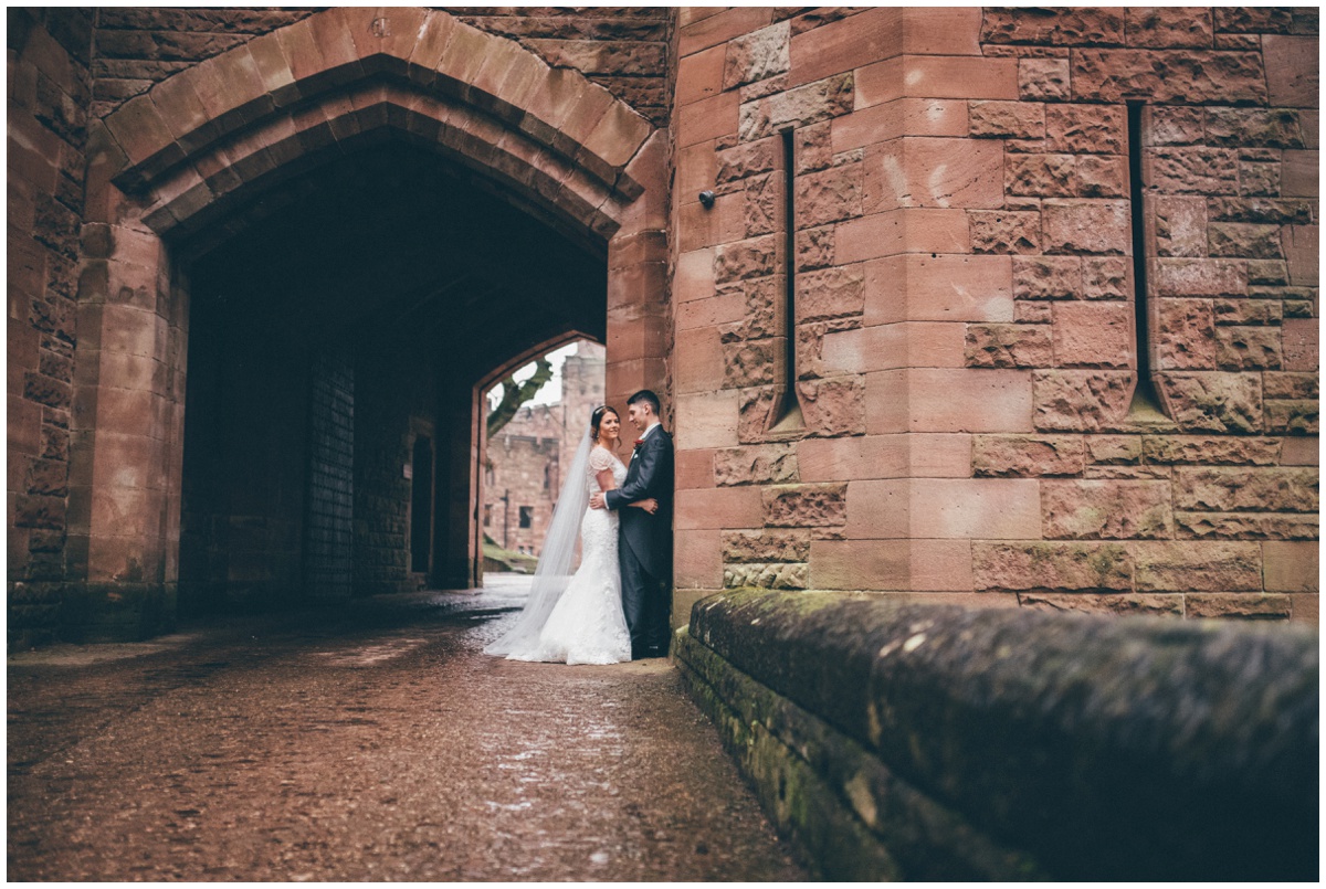 The bride and groom have their wedding photographs taken at the entrance of Peckforton Castle.