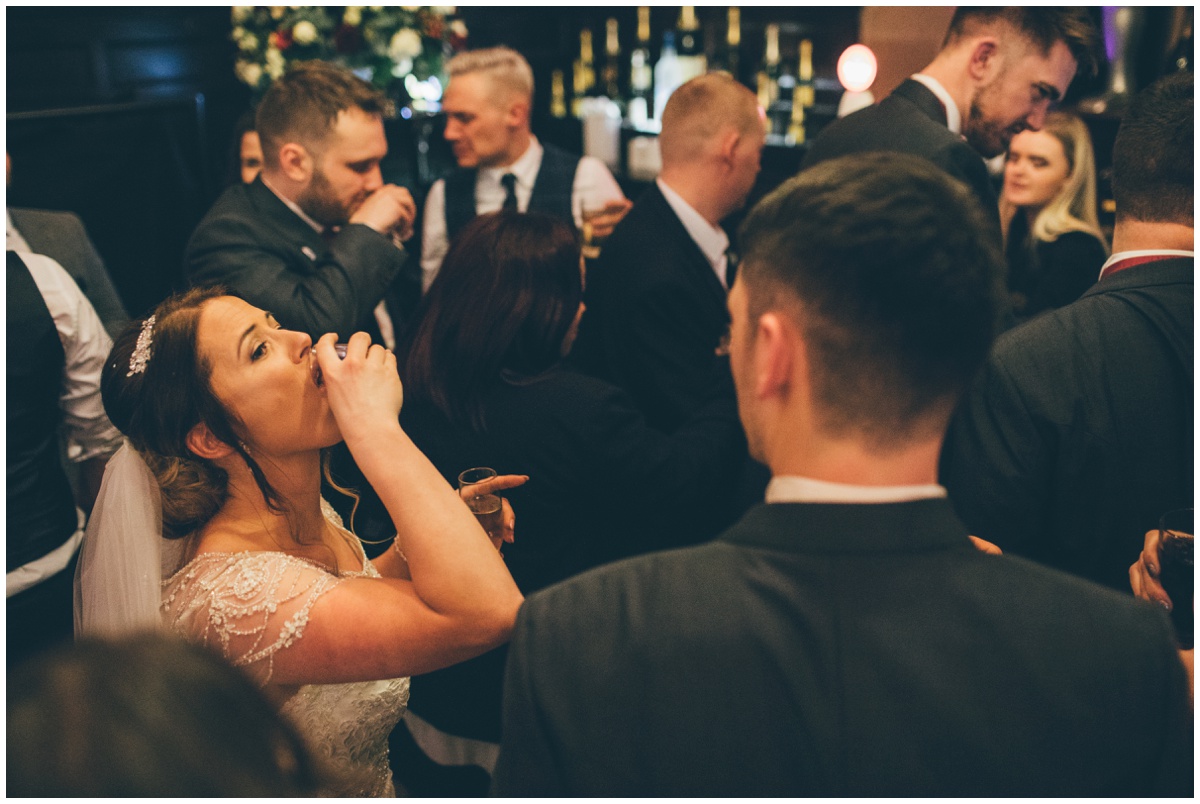 Bride does a shot during her wedding celebrations at Peckforton Castle.