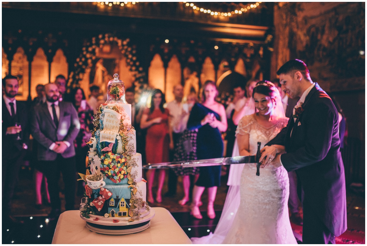 The newlyweds cut their amazing disney-themed wedding cake at Peckforton Castle.