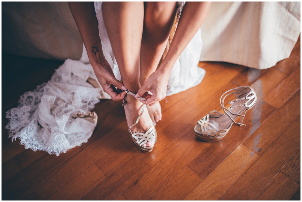 Beautiful bride puts on her high heeled wedding shoes.