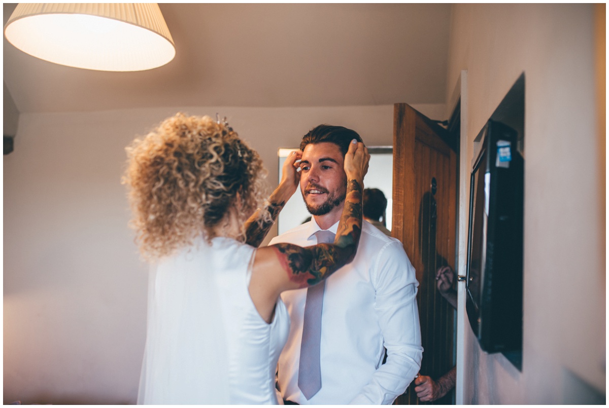 The bride helps her husband with his hair.