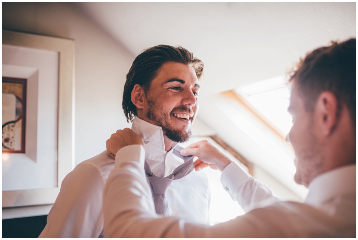 Groomsman helps groom with his tie.