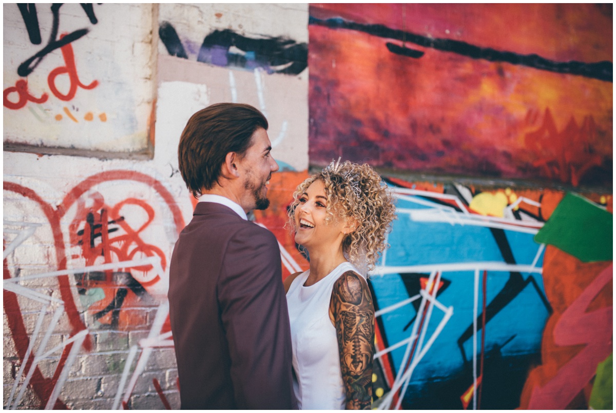 Cool bride and groom pose for wedding photographs in graffiti filled car park in Chester.
