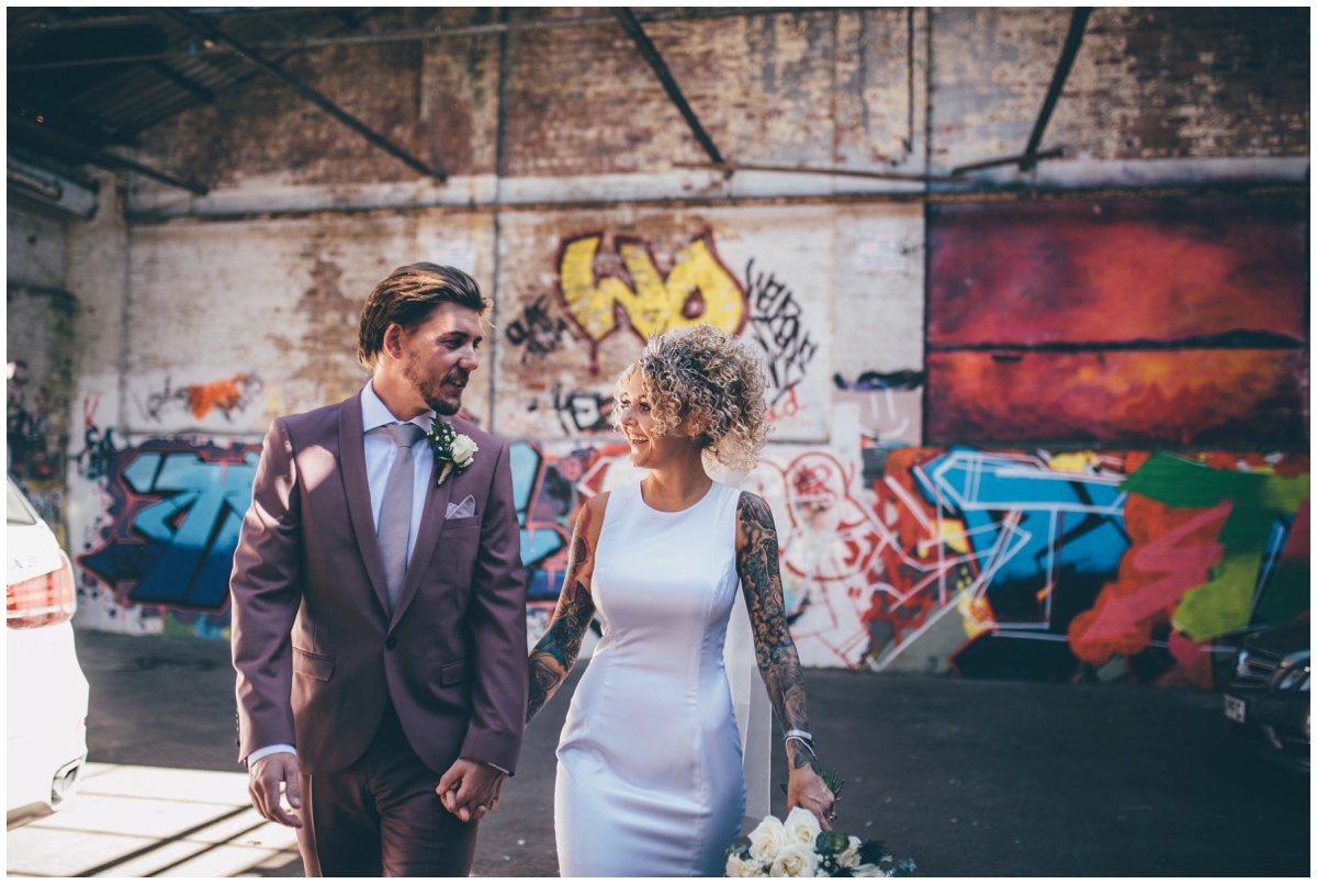 Tattooed bride in a brightly coloured graffiti filled car park.