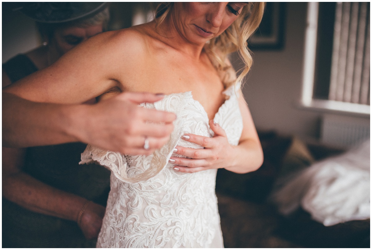 Beautiful bride puts her lace wedding gown on.