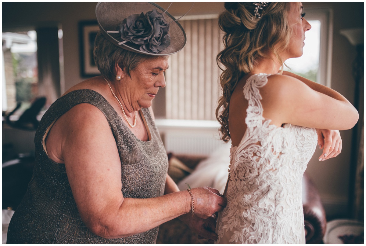 Bride's mum helps her into her wedding gown before her wedding in Staffordshire.