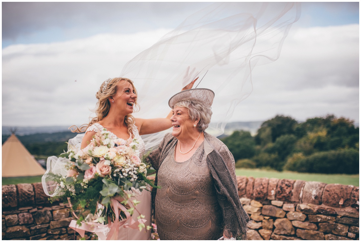 The wind blows the bride's beautiful veil whilst she's having her photograph taken with her mum.