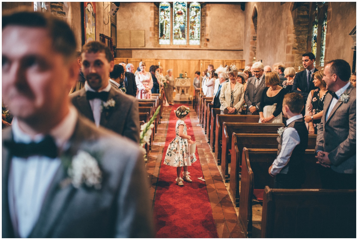 The adorable flower girl walks down the aisle ahead of the bride at St. Matthews church in Staffordshire.