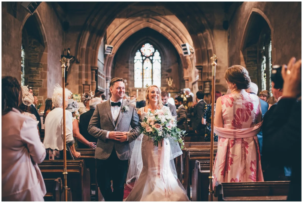 The new bride and groom leave church together as newlyweds.