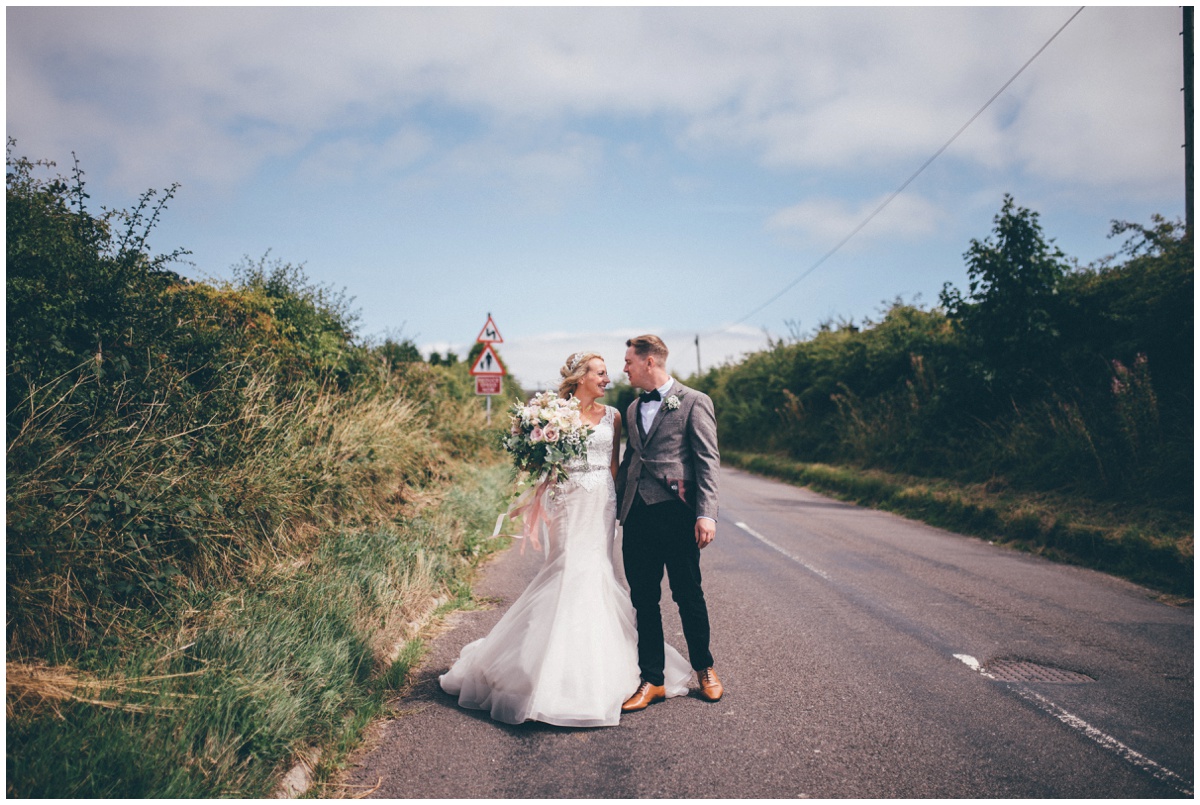 New husband and wife walk towards their blessing along a country road in Leek.