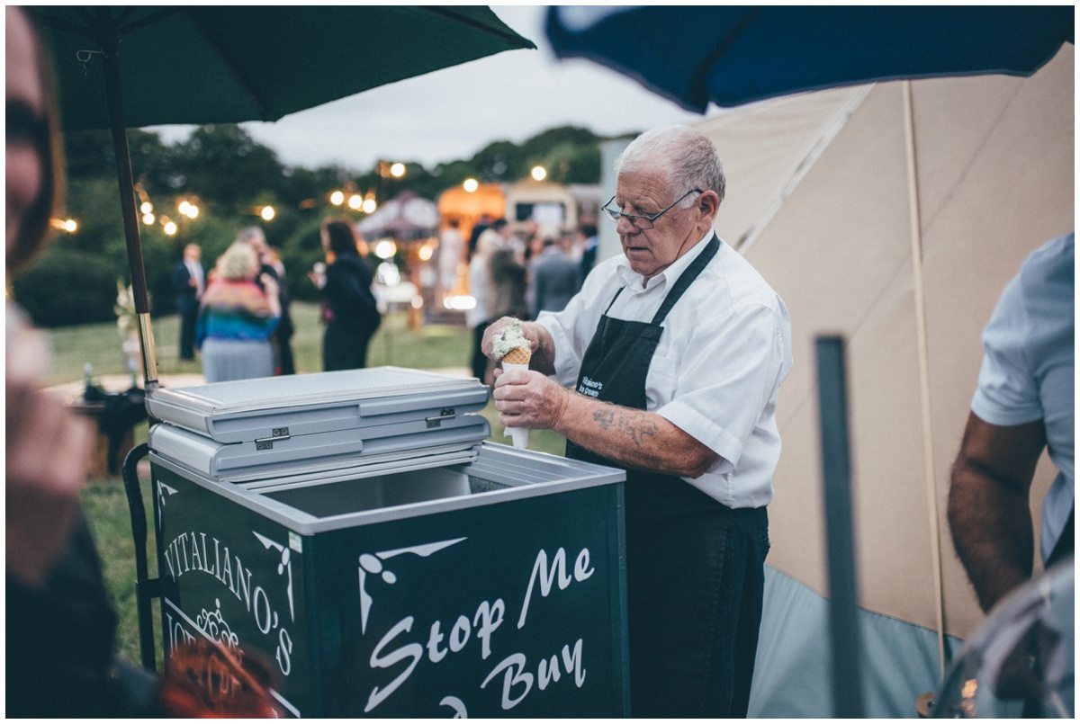 Ice cream man scoops ice cream at a tipi wedding.