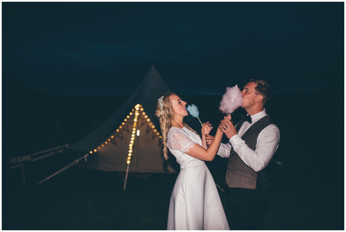 Bride and groom share candy floss at their tipi wedding in Staffordshire.