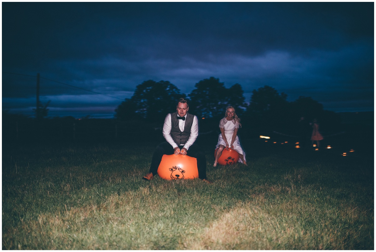 Bride and groom play on space hoppers during their tipi wedding reception in Staffordshire.