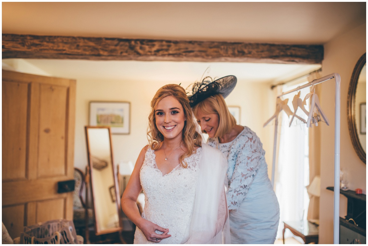 Bride's mum helps her into her dress on the morning of her wedding.