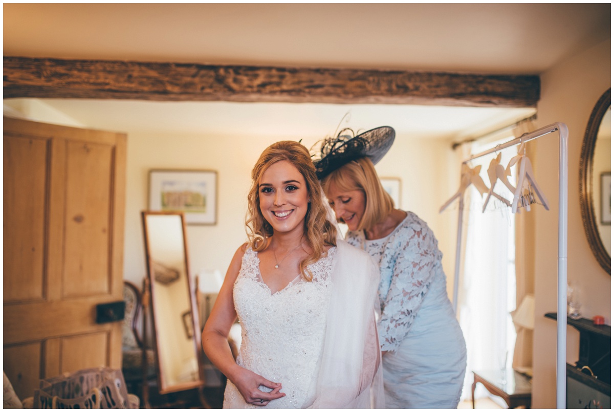 Bride's mum helps her into her dress on the morning of her wedding.