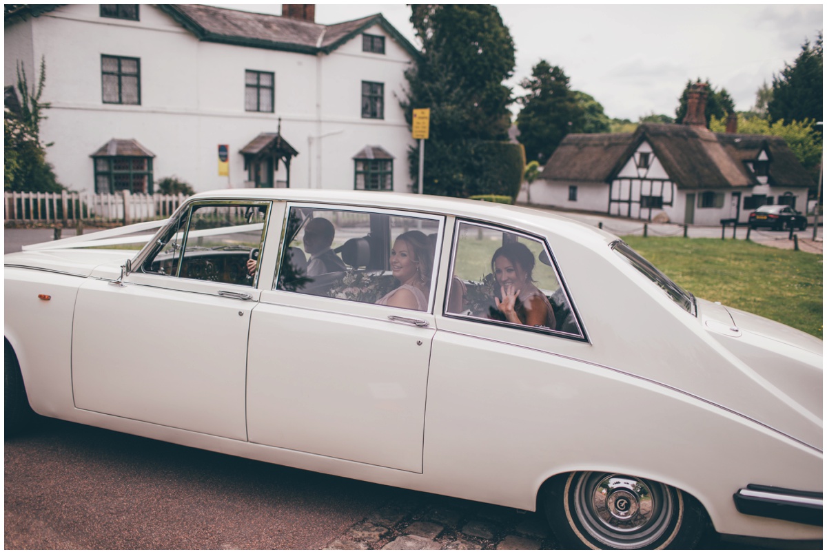 Bridesmaids arrive at St Mary's church in a vintage old wedding car for spring time wedding.